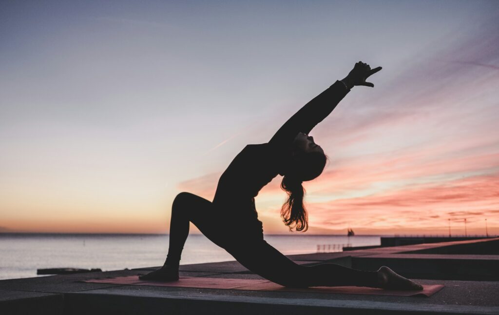 Frau macht Yoga bei Sonnenuntergang
